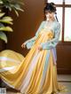 A woman in a yellow and blue hanbok is posing for a picture.