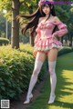 A woman in a pink dress and white stockings posing for a picture.