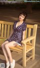 A woman sitting on a wooden bench in a park.