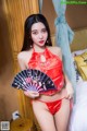 A woman in a red lingerie holding a fan.