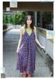 A woman in a colorful dress standing on a bridge.