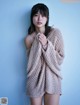 A woman in a beige sweater is posing for a picture.