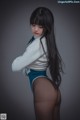 A woman with long black hair wearing a white sweater and blue panties.