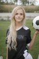 A young woman holding a soccer ball on a field.