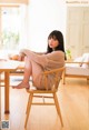 A woman sitting on a wooden chair in a living room.