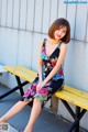 A woman sitting on a yellow bench in a floral dress.