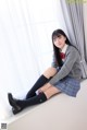 A young woman sitting on a window sill wearing a school uniform.