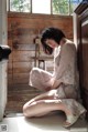 A woman sitting on the floor in front of a window.