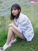 A woman sitting on the grass in a field of flowers.