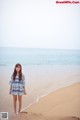 A woman standing on a beach next to the ocean.