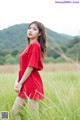 A woman in a red dress standing in a field.