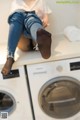 A woman sitting on top of a washing machine.