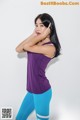 A woman in a purple tank top and blue leggings posing for a picture.