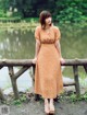 A woman standing on a wooden bridge near a lake.