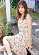 A woman in a colorful dress sitting on a wooden bench.