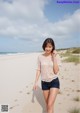 A woman walking on a sandy beach next to the ocean.