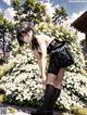 A woman with a backpack standing in front of a bush of flowers.