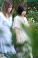 A couple of women standing next to each other in a forest.