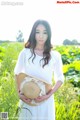 A woman in a white dress holding a straw hat.